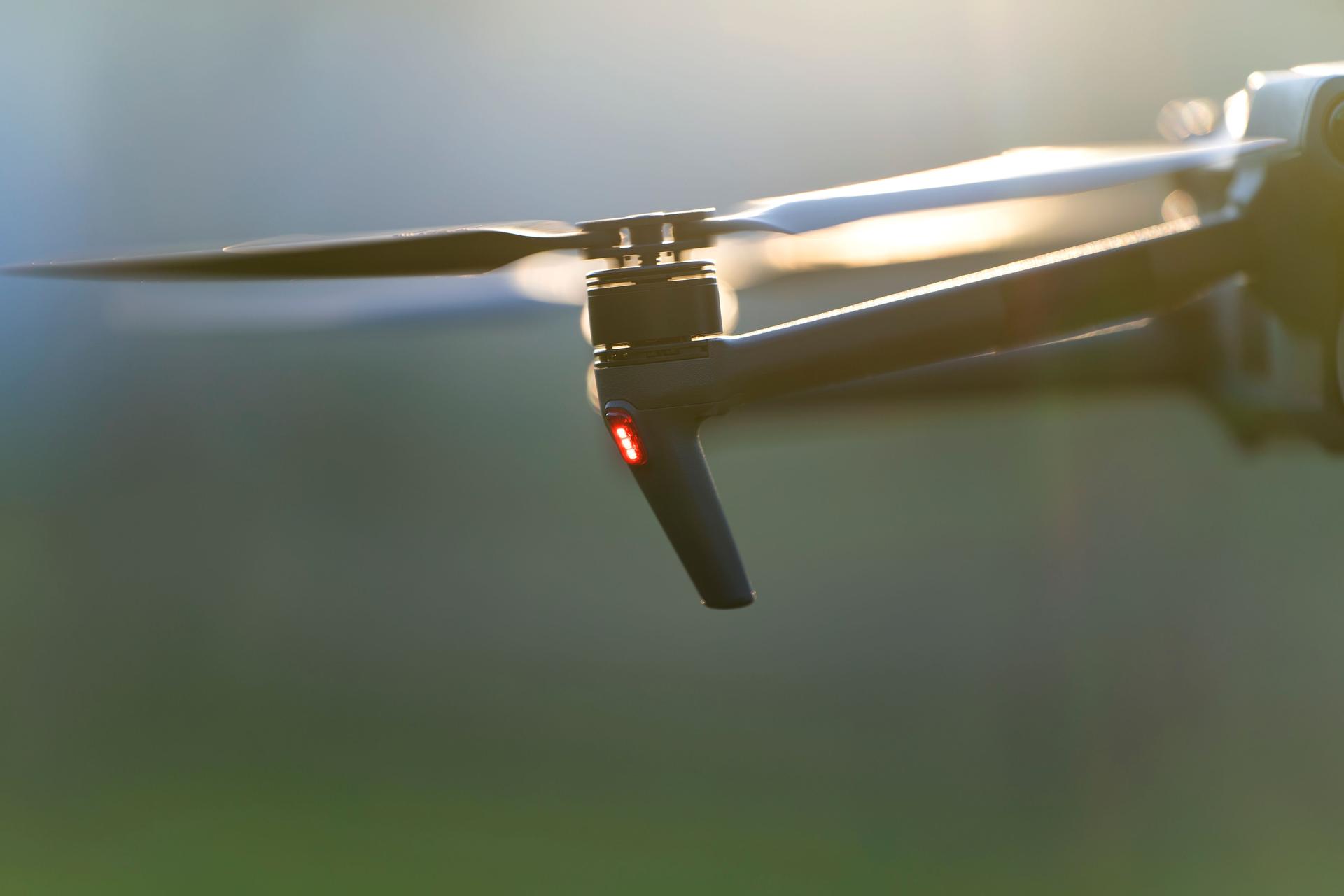 Drone aircraft with blurred fast rotating propellers and video camera flying in air